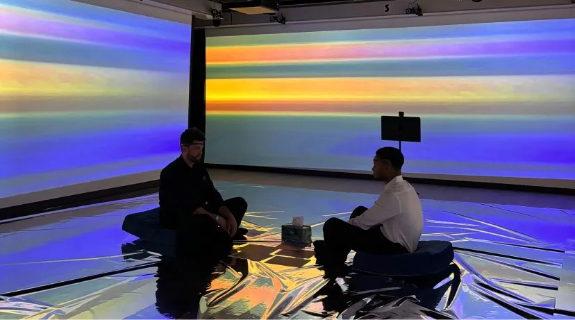 Two participants facing each other in the installation, in blue light